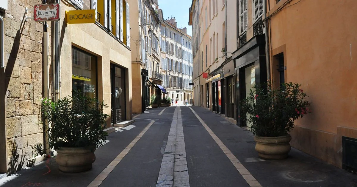 Charmante rue piétonne à Aix-en-Provence présentant une architecture historique et des plantes en pot.