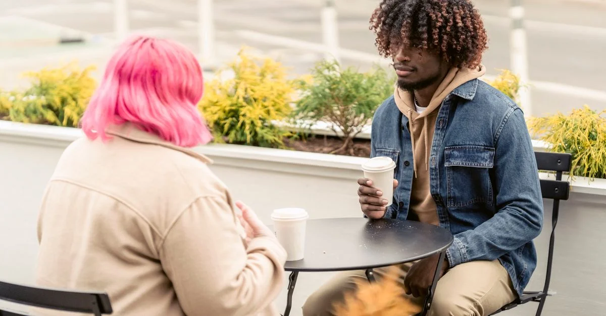 Deux amis appréciant une conversation décontractée autour d'un café en plein air.