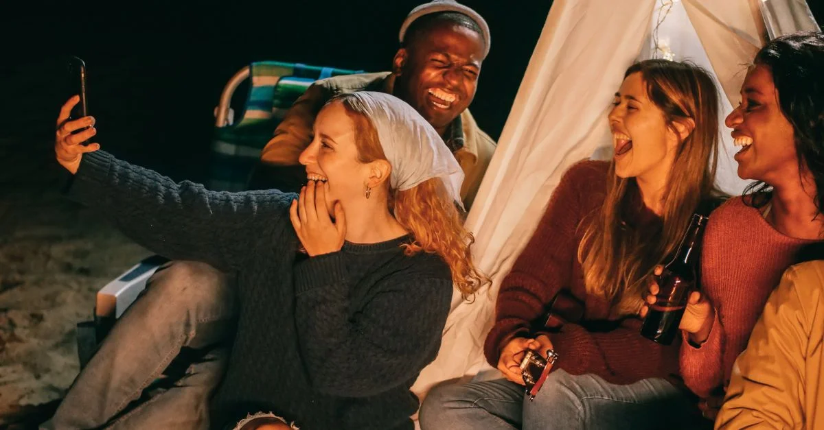 Un groupe joyeux d'amis capturant des souvenirs lors d'un rassemblement autour d'un feu de camp en bord de mer.