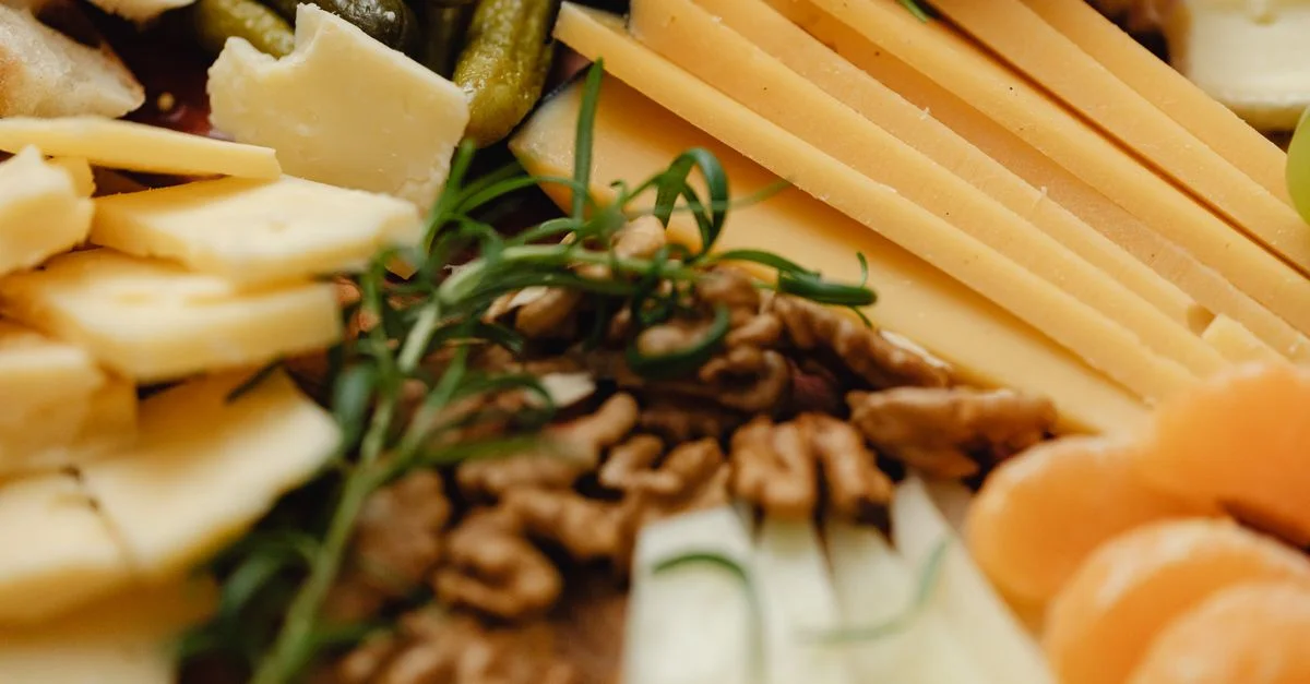 Un gros plan d'un plateau de fromages variés avec des noix, des fruits et des cornichons, parfait pour un repas gastronomique.