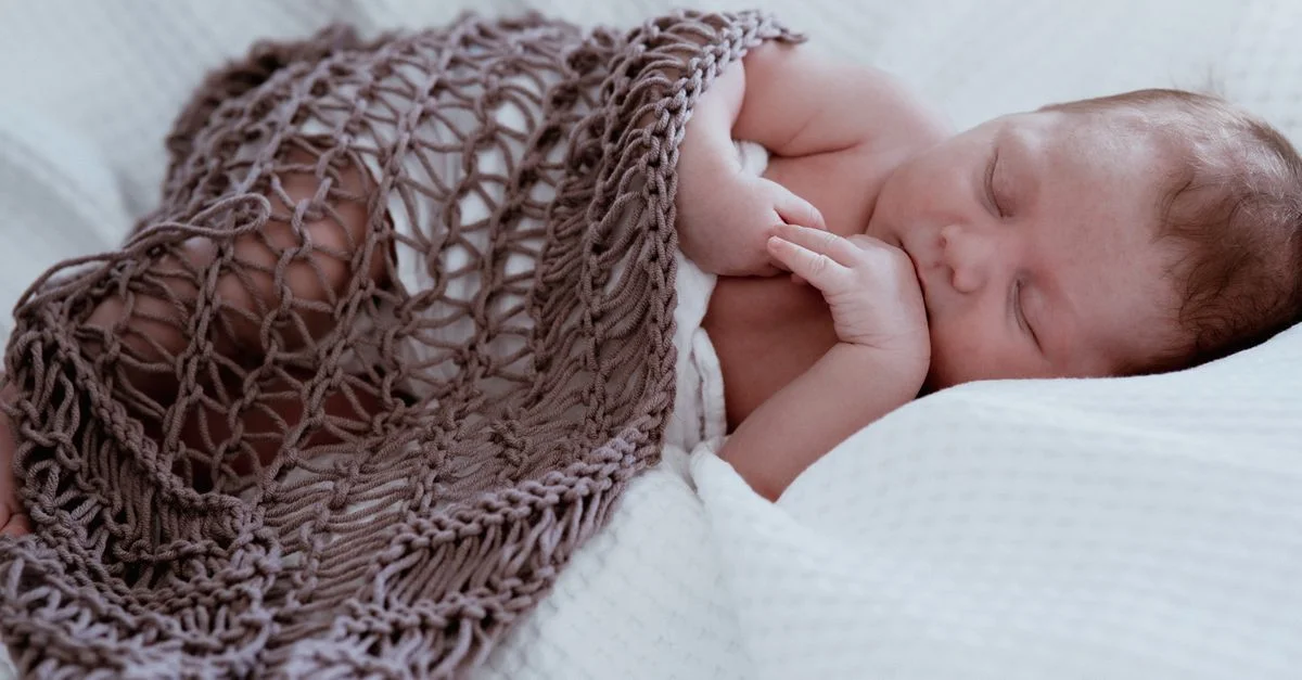 Un gros plan serein d'un nouveau-né dormant paisiblement sous une couverture en tricot.