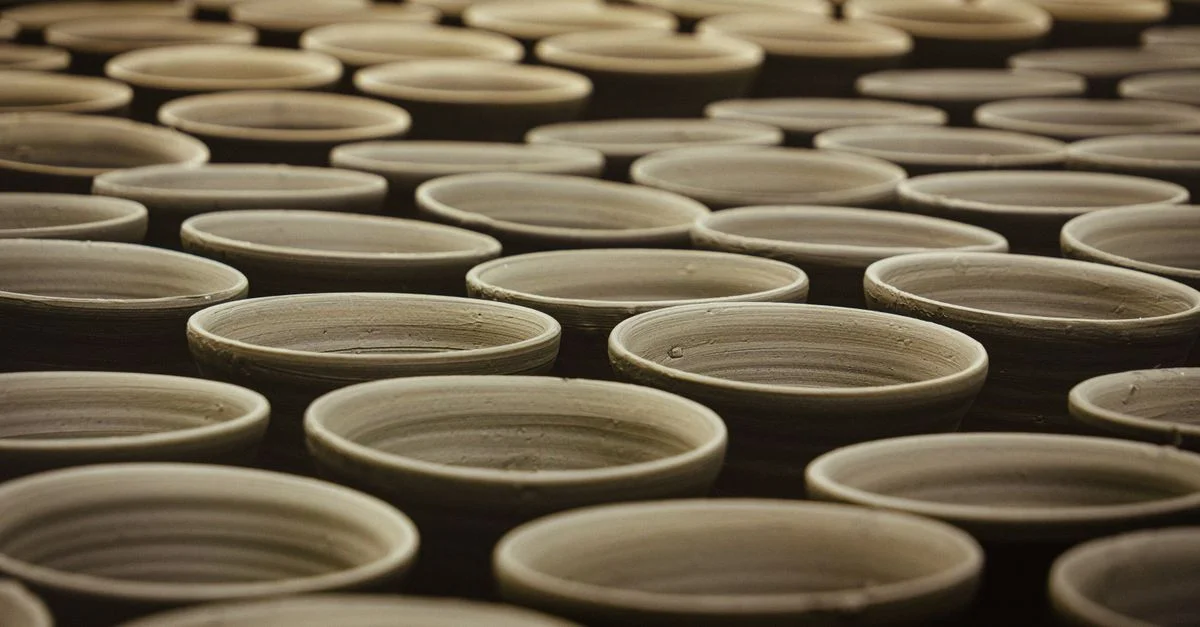 De nombreux pots en argile faits à la main alignés dans un atelier de poterie traditionnel.