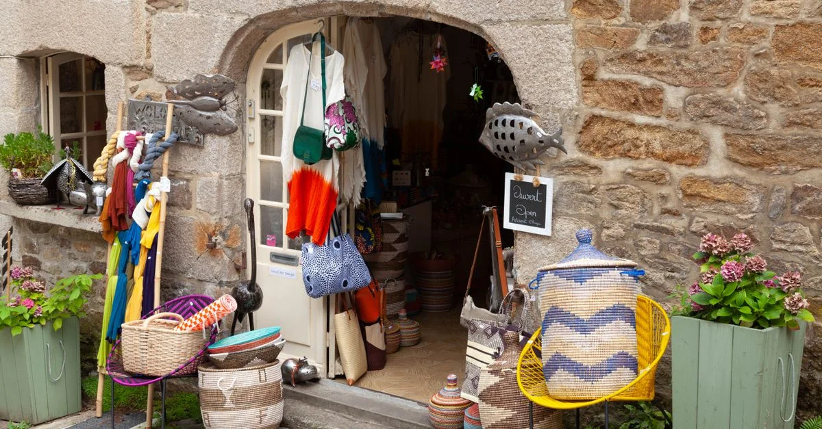 Magasin d'artisanat coloré à Dinan, Bretagne, avec des paniers et des textiles en exposition.