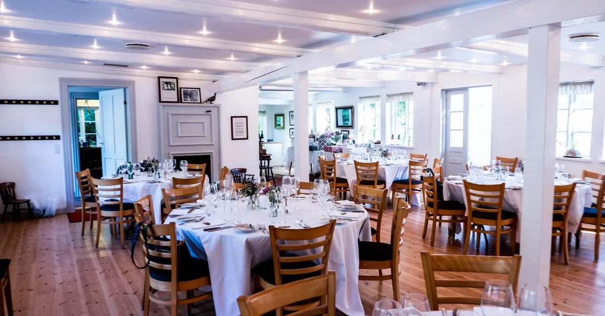 Configuration charmante de réception de mariage avec des tables rondes, des chaises en bois et de la vaisselle élégante.