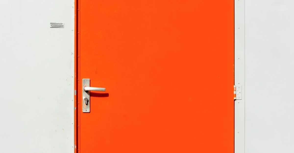 Porte orange vif avec poignée en argent contre un mur blanc, parfaite pour des concepts de design moderne.