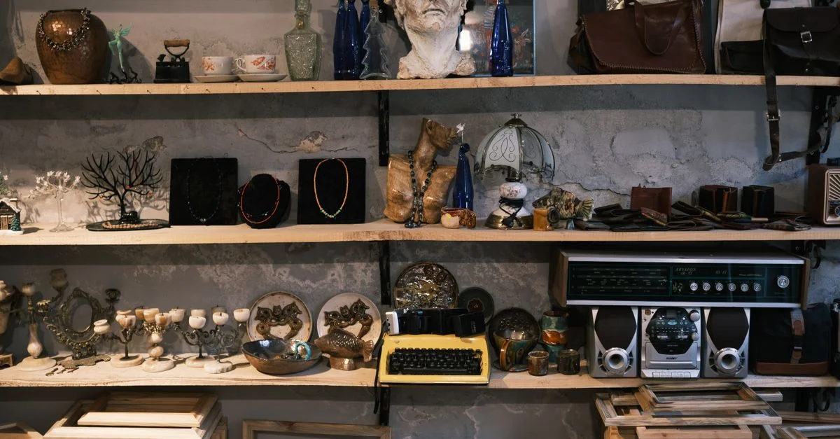 Une étagère de boutique vintage remplie d'antiquités éclectiques, d'objets de décoration et d'une machine à écrire.