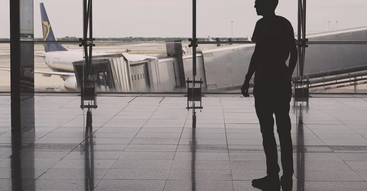 Silhouette d'un homme à l'aéroport El Prat avec des reflets d'avion sur les murs vitrés.