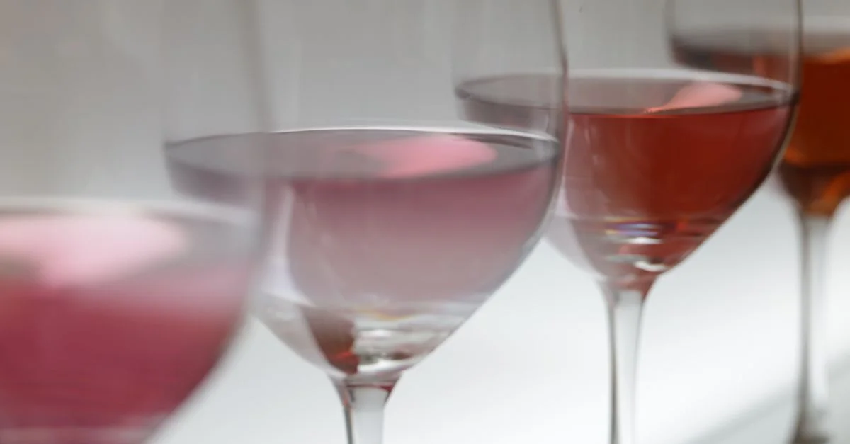 Gros plan sur divers verres à vin remplis de rosé dans un éclairage doux, parfait pour des événements de dégustation de vin.