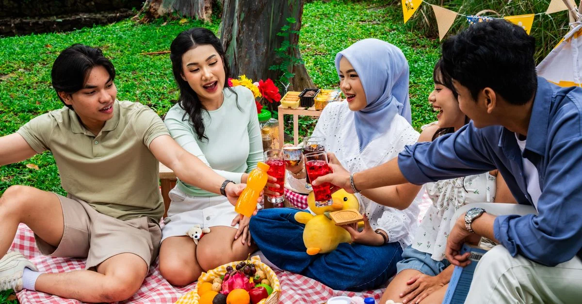Un groupe d'amis profite d'un pique-nique coloré en plein air en Indonésie, célébrant l'amitié autour de collations et de boissons.
