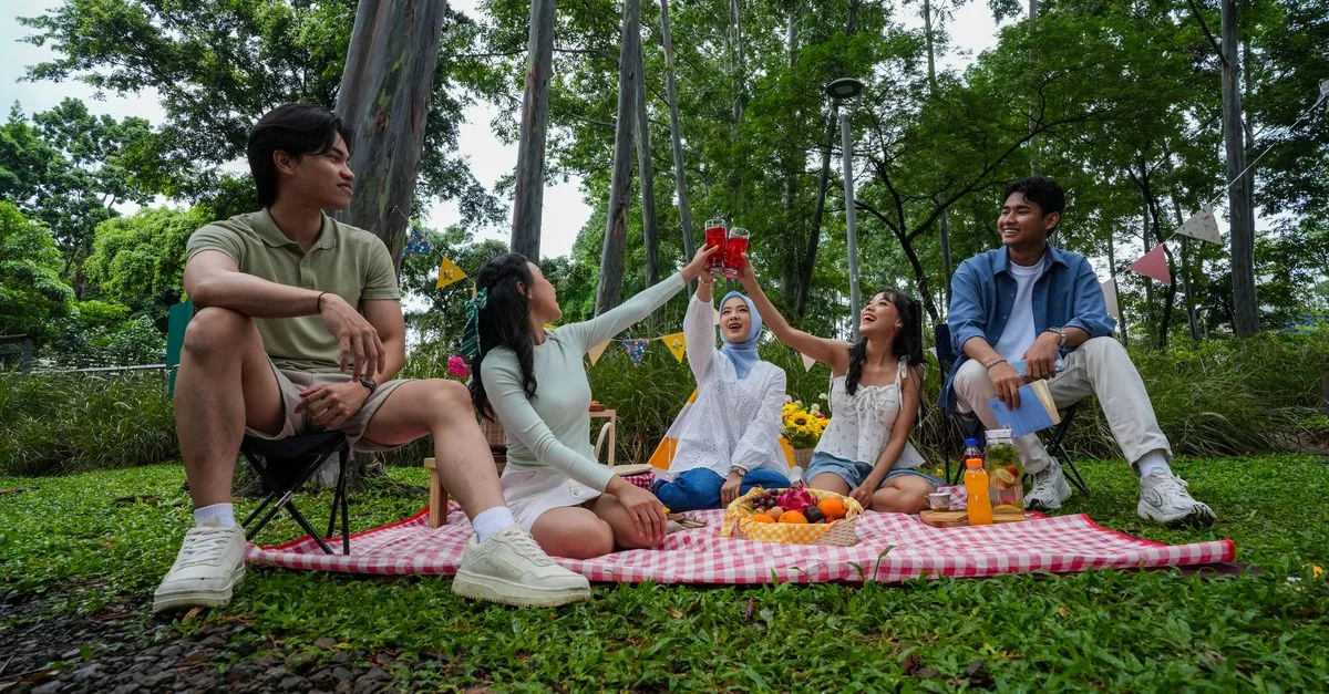 Des amis profitent d'un joyeux pique-nique en plein air à Jakarta, savourant boissons et en-cas par une journée ensoleillée.
