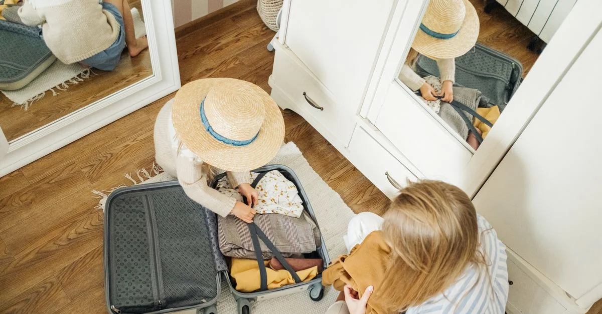 Enfant préparant une valise avec l'aide de sa mère, se préparant pour un voyage d'été.