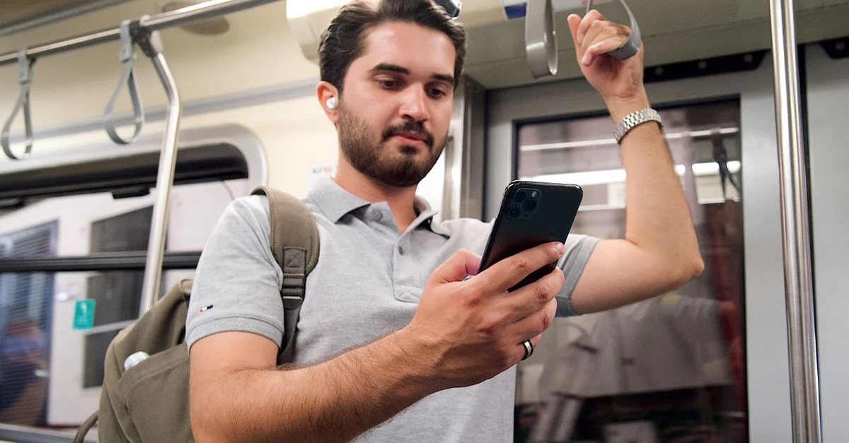 Jeune homme utilisant un smartphone avec un sac à dos dans les transports publics.